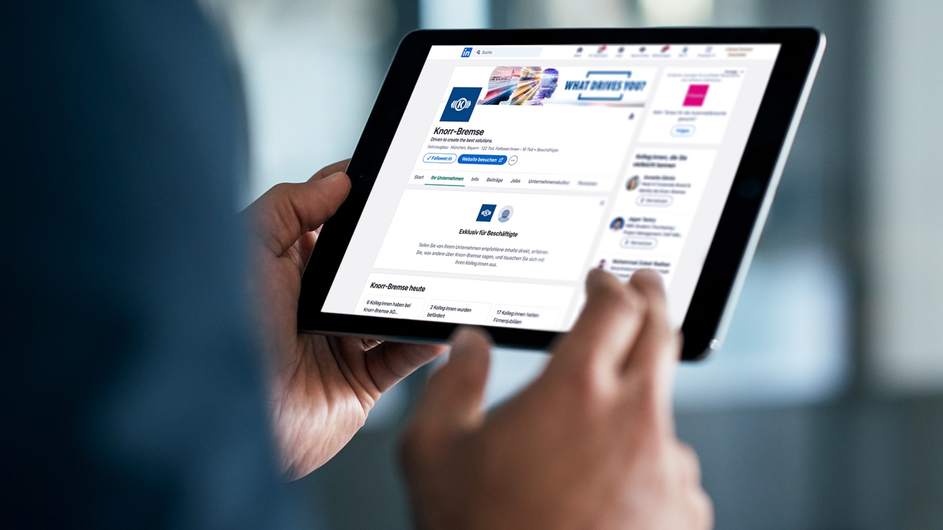Close-up of two hands holding a tablet on which the Knorr-Bremse LinkedIn channel is displayed